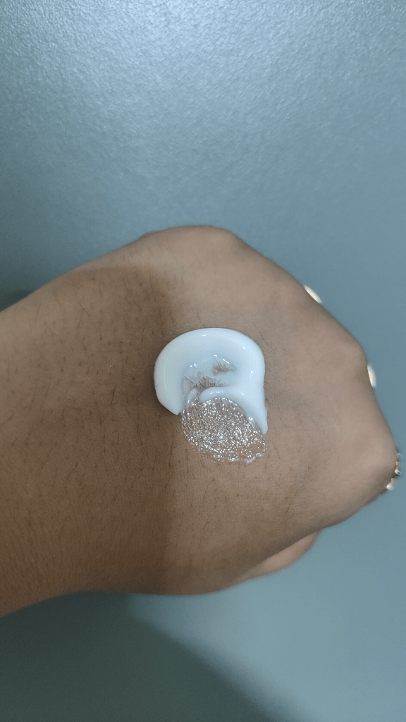 A dollop of The Face Shop Pomegranate & Collagen Volume Lifting Cream on a hand, showcasing its creamy texture against a neutral background.